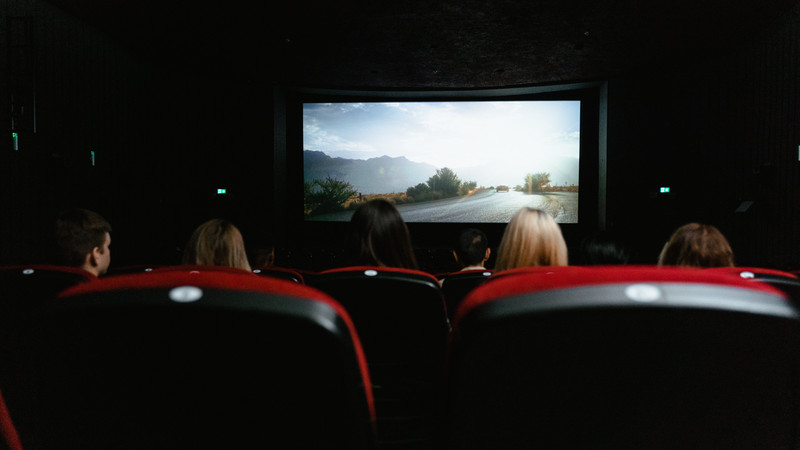 En gruppe mennesker sitter i en kinosal og ser film på et lerret. Foto.