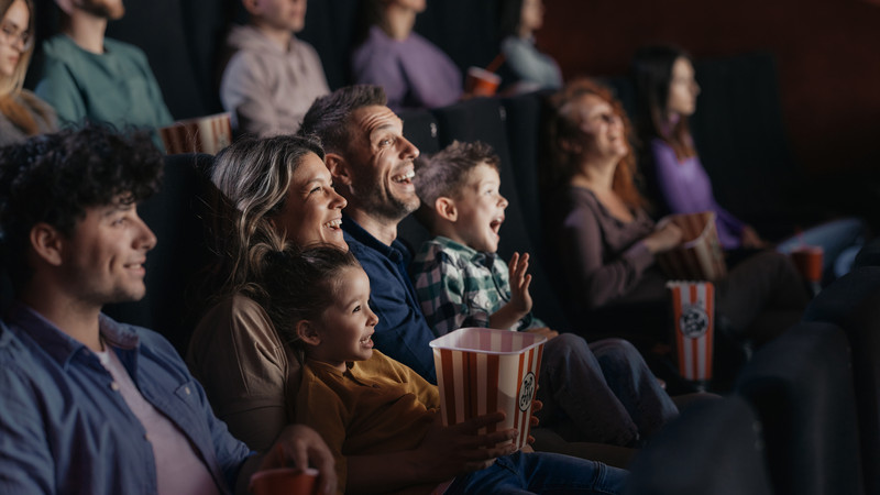 Foto. En gruppe publikummere i en kinosal som ser på film, smiler og ler.