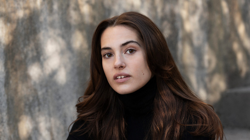 Foto. En ung dame med langt brunt hår og brune øyne.