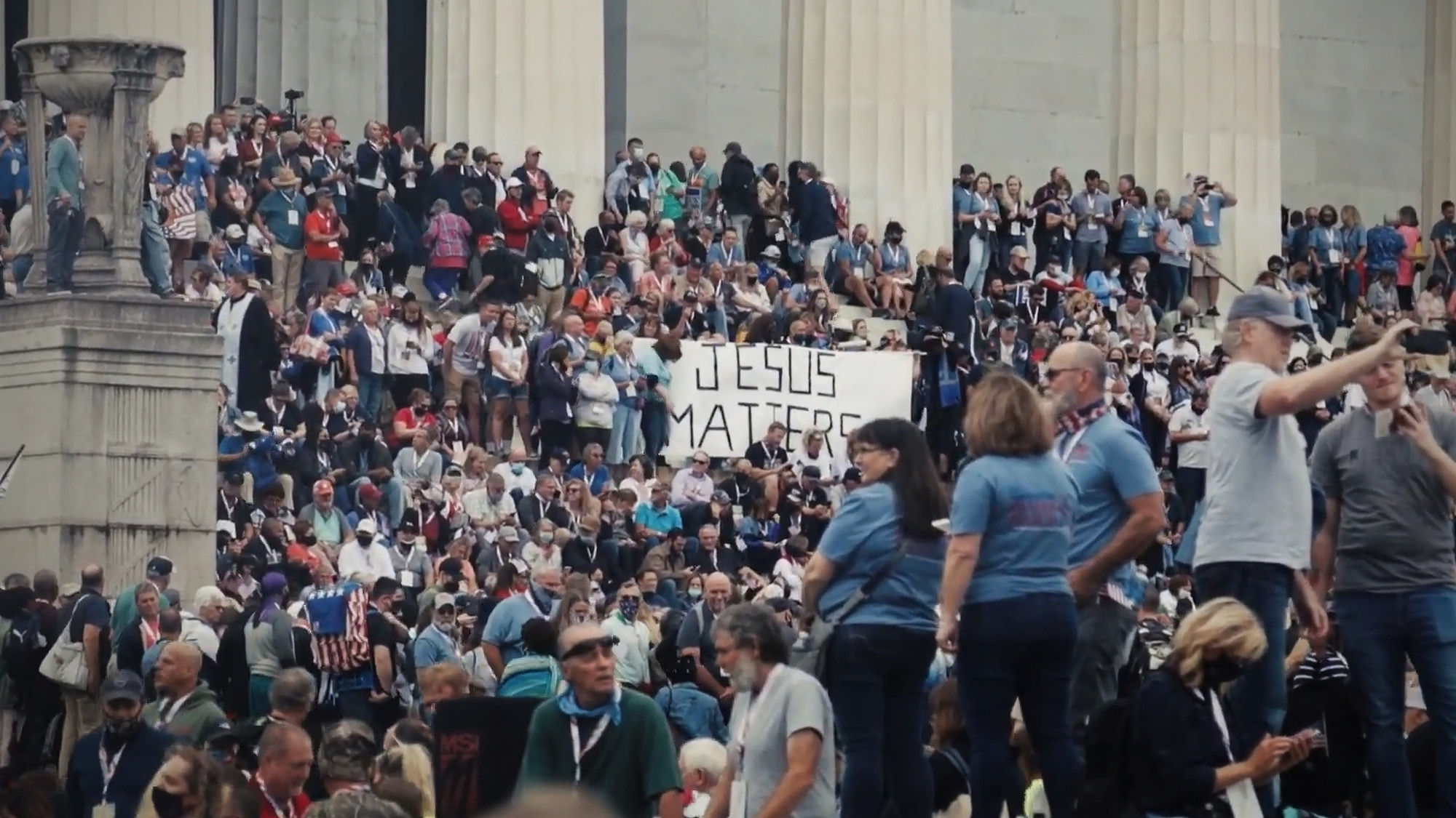 En stor folkemengde samlet i og foran trappen til en stor bygning. Noen holder et banner med teksten: Jesus Matters. Foto.