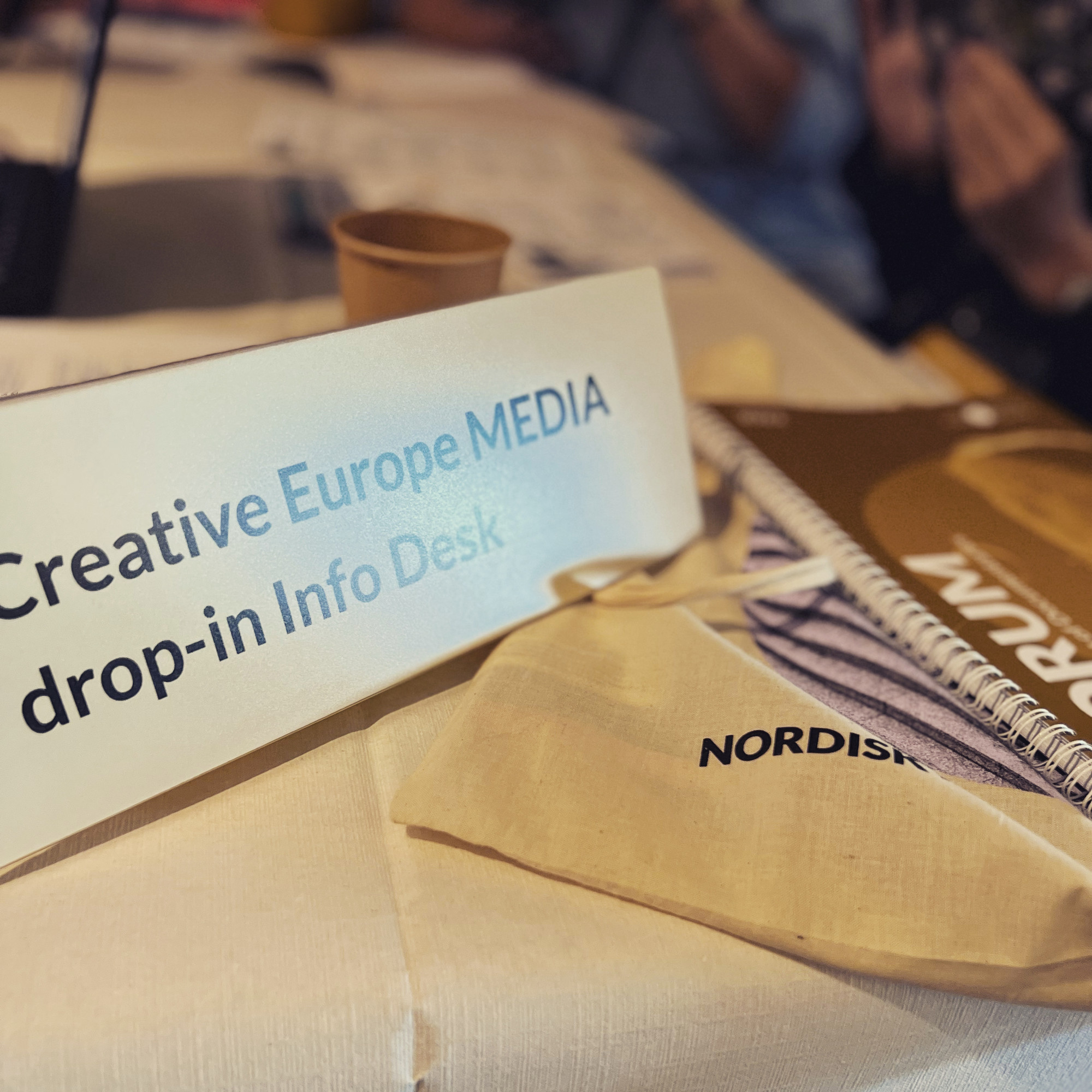 Et bord med bl.a. et skilt med teksten: Creative Europe MEDIA drop-in Info Desk. Foto.