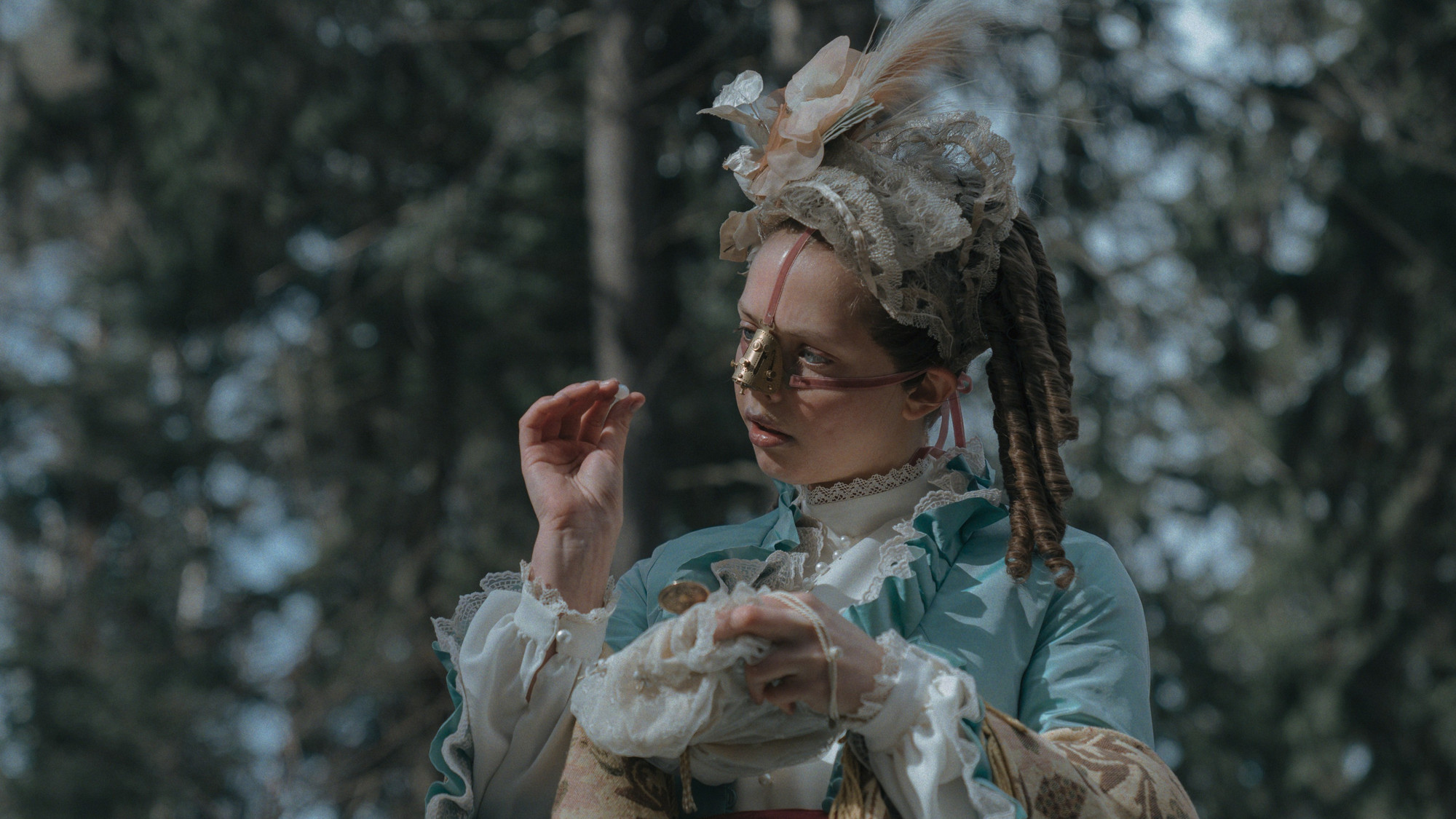 Foto. En ung kvinne med neseskjold i pent tøy holder en pille i den ene hånden.