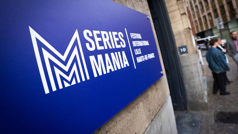 Foto. Blått skilt på et murbygg.