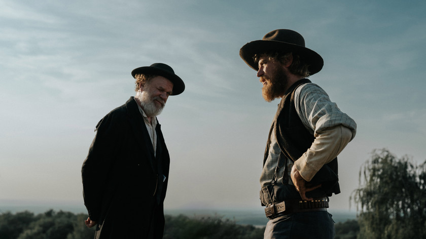 Foto. To menn med hatt i profil. Landskap skimtes i bakgrunnen.